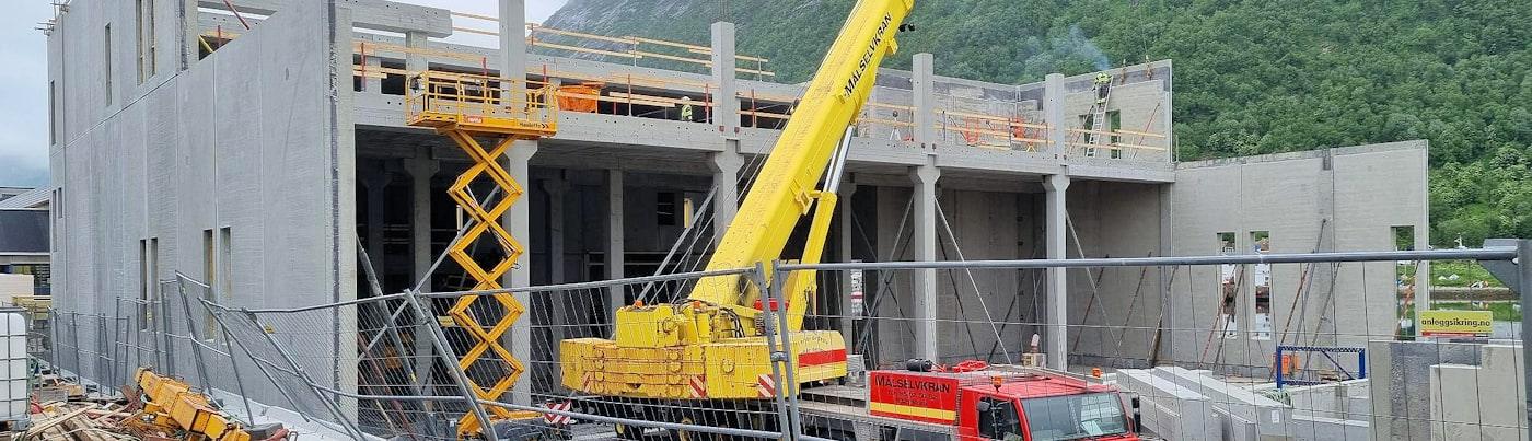 Gul mobilkran ved betongvegger på Husøy